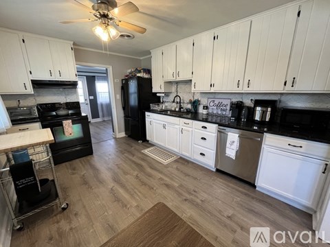 A kitchen with white cabinets and a black fridge.