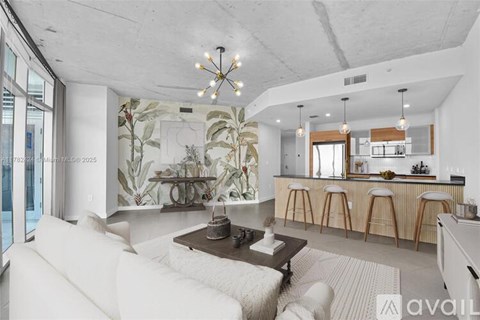 A modern living room with a large painting on the wall and a bar area in the background.