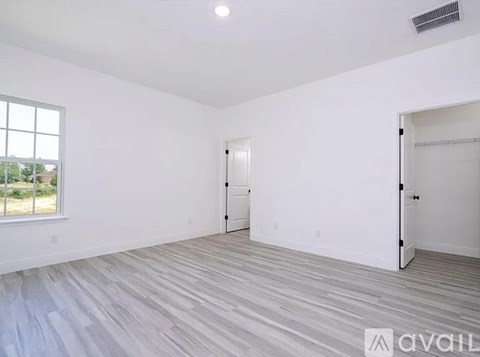 A spacious room with a large window and a wooden floor.