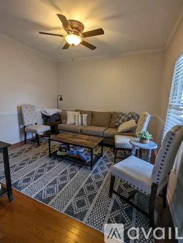 A living room with a patterned rug and a ceiling fan.