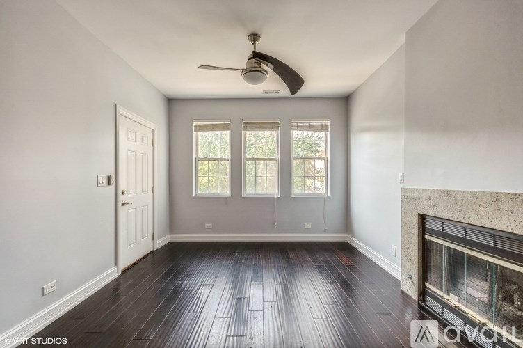 A spacious room with a fireplace and a ceiling fan.