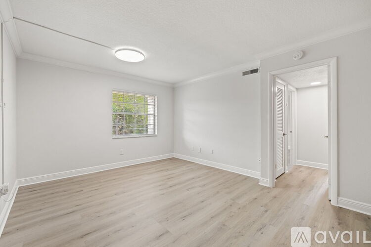 A spacious room with wooden flooring and a window.