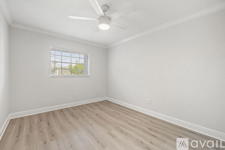 A room with a ceiling fan and a window with blinds.