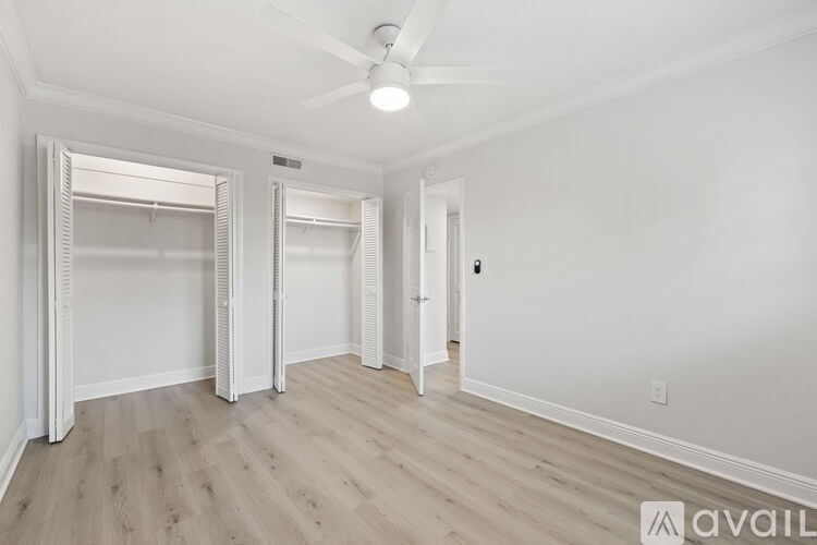 A spacious room with a ceiling fan and wooden flooring.