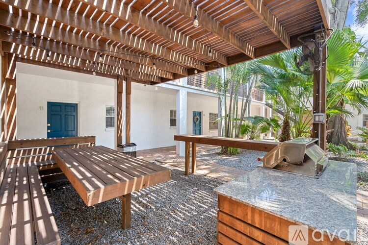 A wooden table and benches are set up under a wooden pergola.