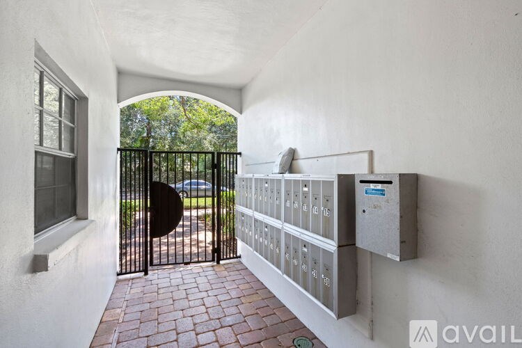 A black gate leads to a driveway with a brick pathway.