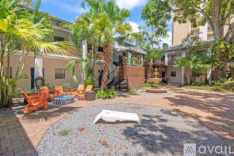 A patio area with a white couch and a table surrounded by trees.