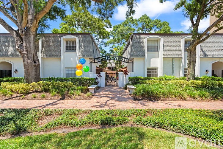 A white house with a grey roof and a garden in front.