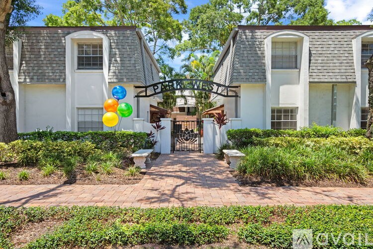 A white house with a black roof and a garden in front.