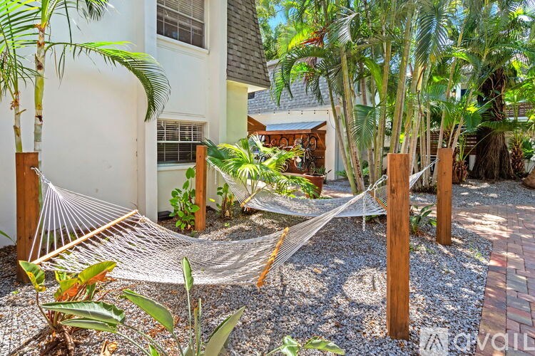 A white house with a hammock in front of it.