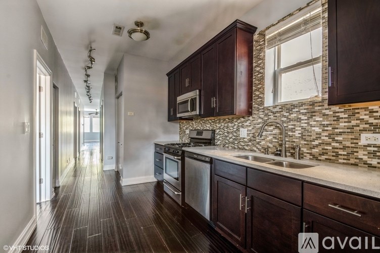 A kitchen with dark wood cabinets and a stone backsplash.
