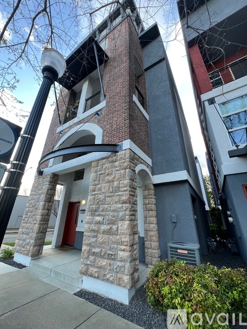 A building with a red door and a stone pillar in front.
