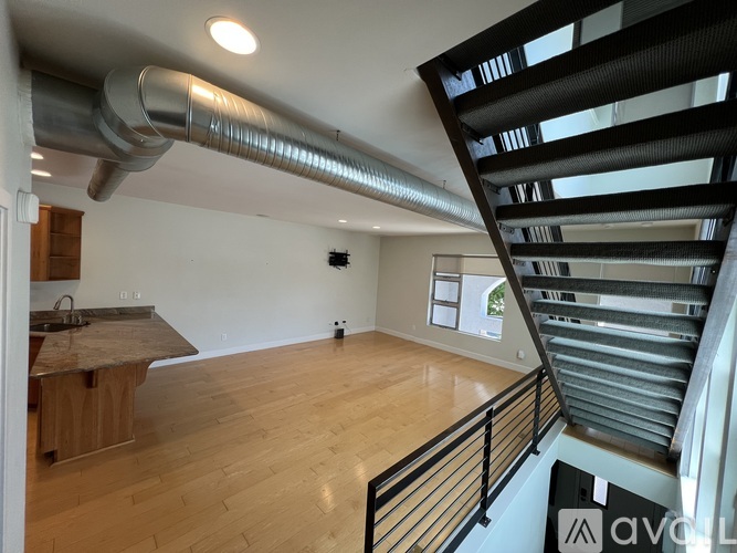 A modern kitchen with wooden floors and a stainless steel exhaust pipe.