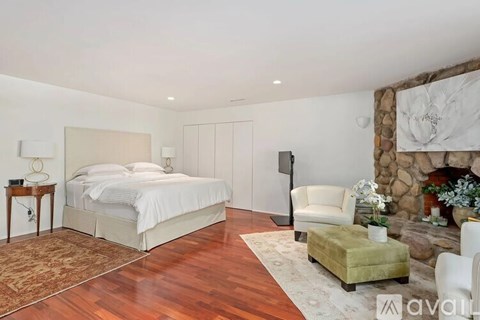 A bedroom with a large bed and a fireplace.