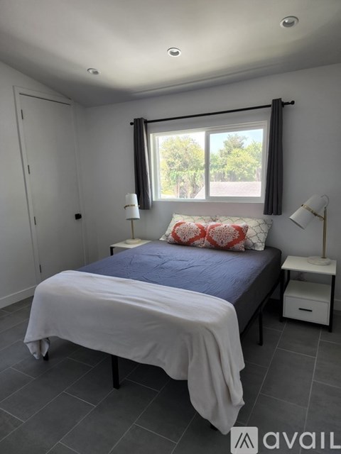 A bedroom with a bed, nightstand, and window.