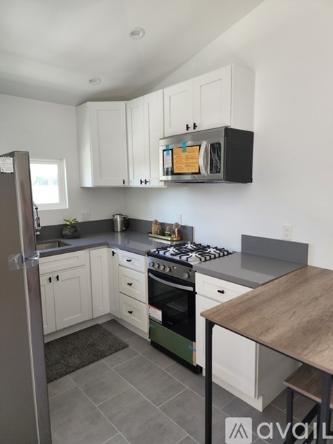 A kitchen with white cabinets and a black microwave above the stove.