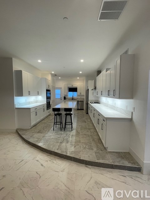 A kitchen with white cabinets and a marble floor.