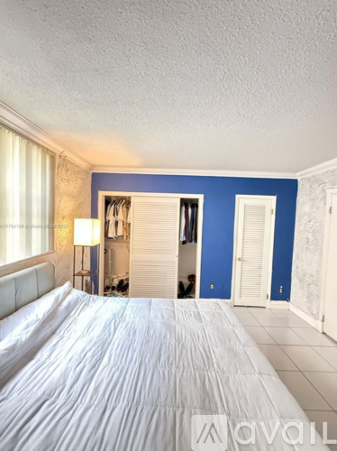 A bedroom with a white bed and a blue wall.