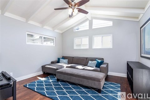 A living room with a grey couch and a ceiling fan.