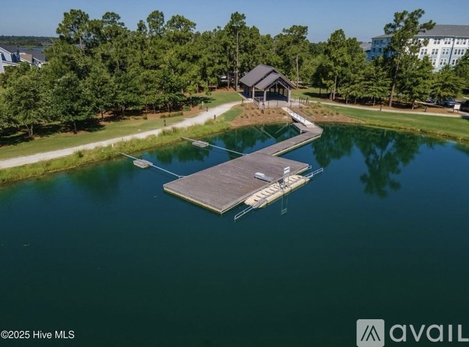 A dock extends into a body of water with a building in the background.