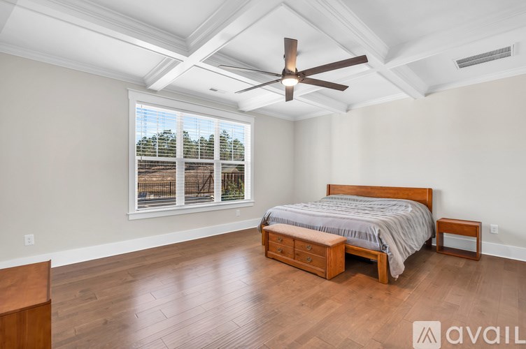 A bedroom with a bed, nightstand, and window with a view of trees.