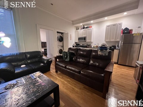 A living room with a black leather couch and a coffee table.