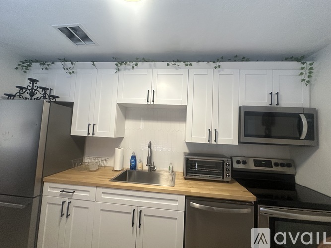 A kitchen with white cabinets and a stainless steel refrigerator.