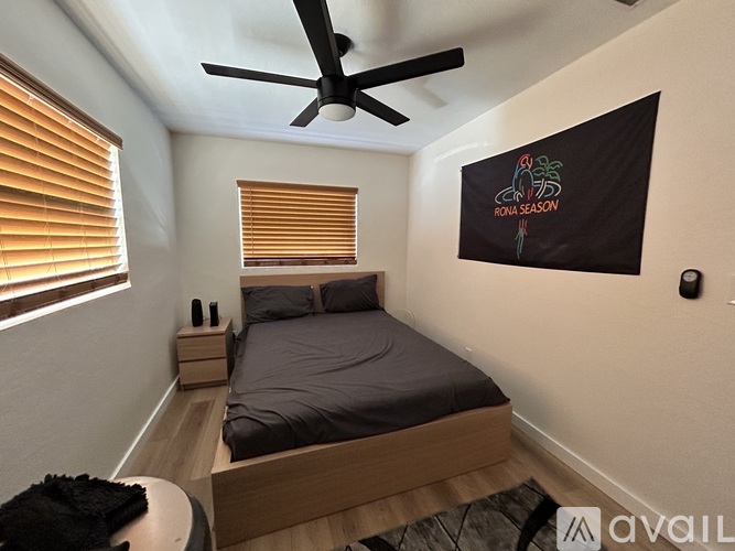 A bedroom with a bed, ceiling fan, and a window with blinds.