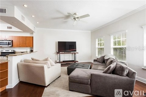 A living room with a grey couch and a television on a stand.