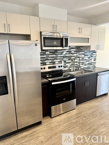A kitchen with a stainless steel refrigerator and a microwave above the stove.