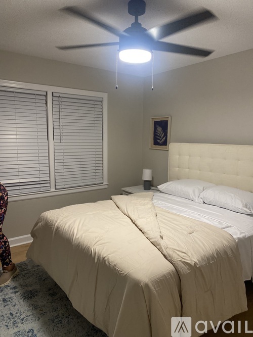 A bedroom with a large bed and a ceiling fan.
