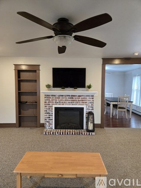 A living room with a fireplace and a television mounted above it.