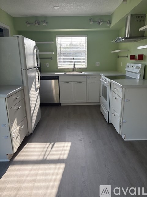 A kitchen with white appliances and green walls.