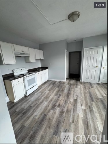 A kitchen with white cabinets and a wooden floor.
