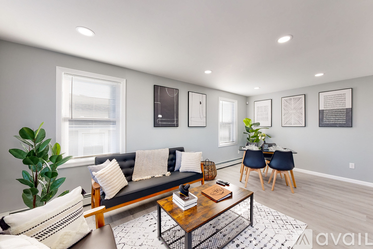 A living room with a black couch, a coffee table, and a plant.