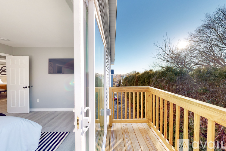 A balcony with a wooden railing and a view of trees and buildings outside.
