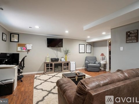 A living room with a brown leather couch and a white rug.