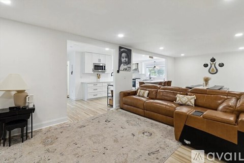 A living room with a brown leather couch and a piano.