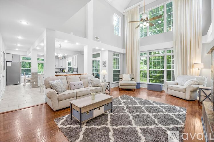 A spacious living room with a large rug and a ceiling fan.