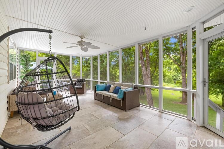 A sunroom with a hanging chair and a couch.