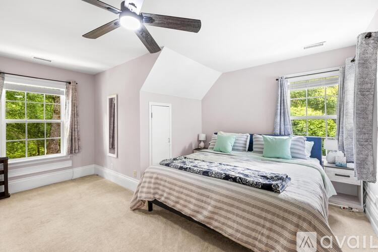 A bedroom with a bed, a ceiling fan, and two windows.