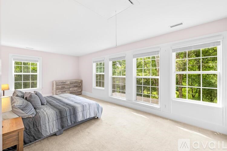 A bedroom with a bed, nightstand, and a window with a view of trees.