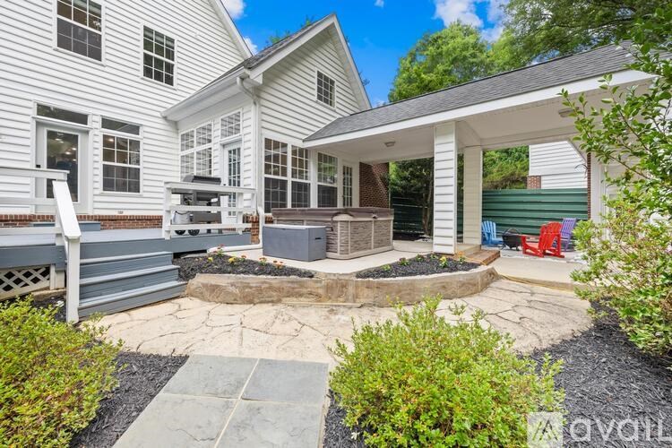 A white house with a covered patio and a fire pit in the backyard.