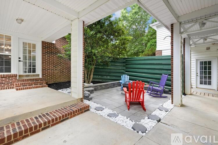 A porch with a white roof and a brick wall with a red chair and a purple chair.