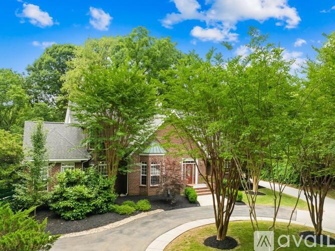 A house with a driveway and trees in front of it.