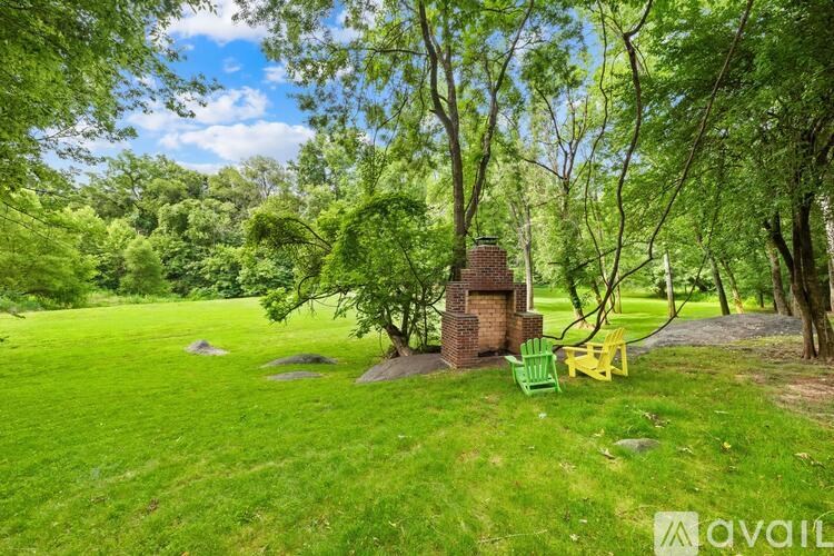A lush green field with a brick chimney and a yellow chair.