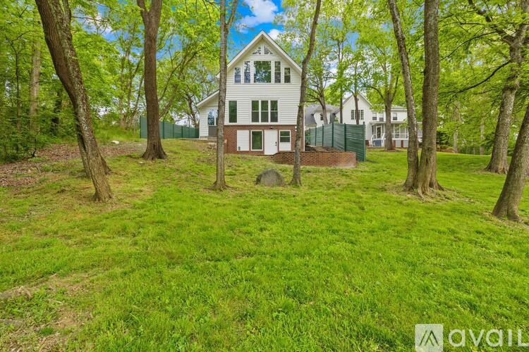A house is surrounded by trees in a grassy area.
