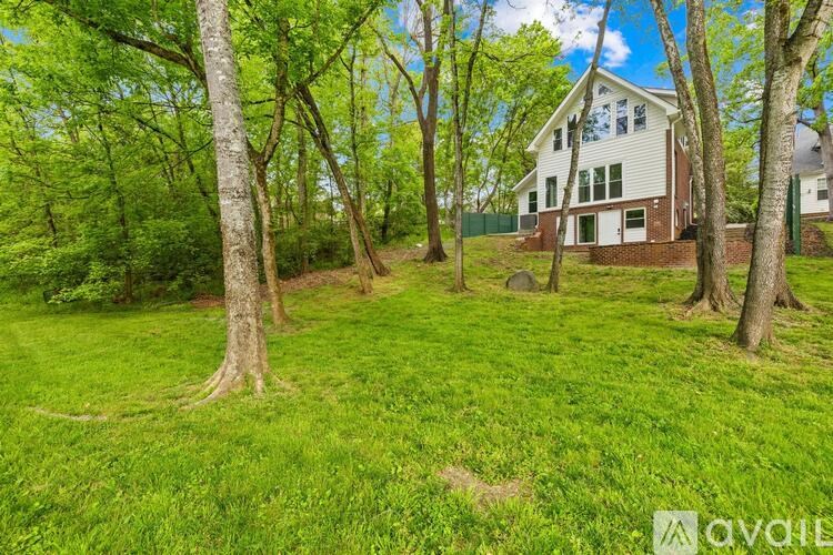 A house is surrounded by trees in a grassy area.