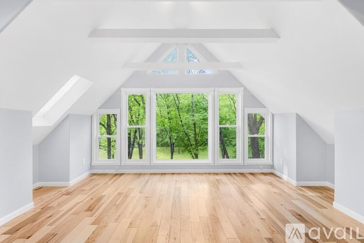 A room with wooden floors and a large window with a view of trees.