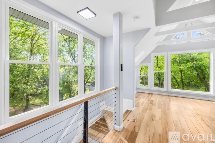 A room with a staircase leading to the second floor with a view of trees outside the window.